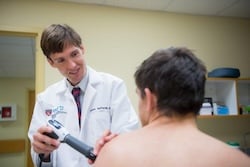 Photo of Dr. Adam S Tenforde, MD using a shockwave device on a patient.