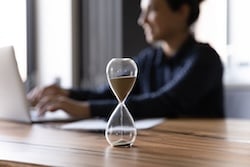 Close up hourglass measuring time and a businesswoman working