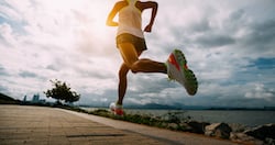 Fitness woman running training for marathon on sunny coast trail