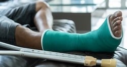Person resting on a couch with a green cast on their leg and crutches beside them, indicating recovery from a leg injury.